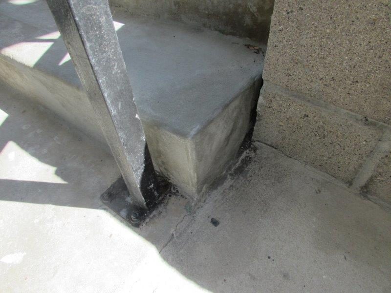 Rebuilt concrete stair corner beside a railing post on an AWC project